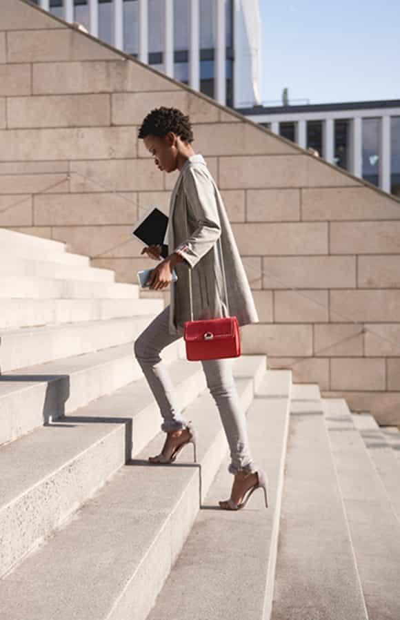 confident sales woman walking up the stairs on her way to a meeting with clients where she is going to use the Challenger approach to drive the deal forward