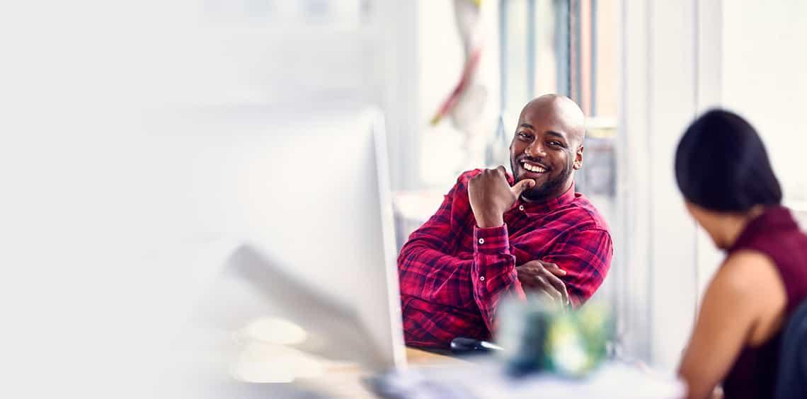 two sales professionals sitting at a desk looking happy because they have the soft selling skills they need to succeed thanks to richardson's six critical skills training program