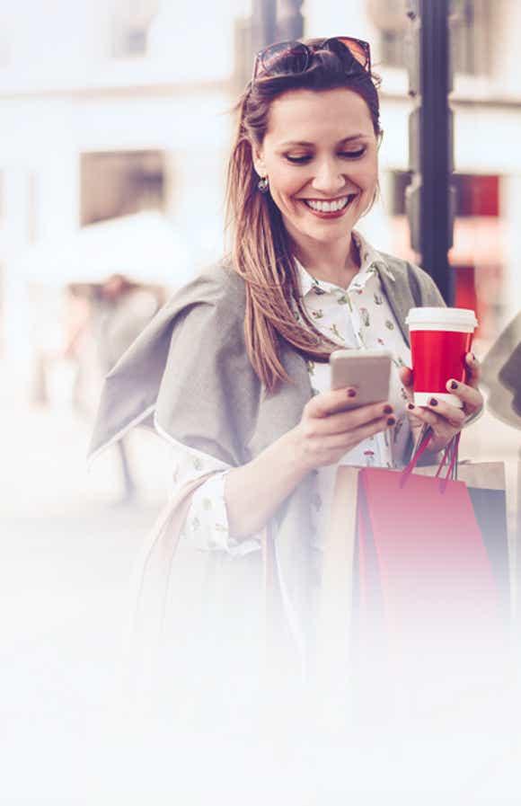 young female sales professional using her cell phone on a city street to complete a simple training reinforcement exercise on Richardson's QuickCheck solution.