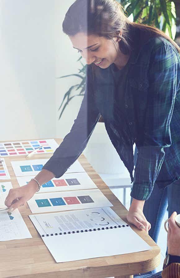 woman leaning over a desk with many papers designing a custom sales training program 