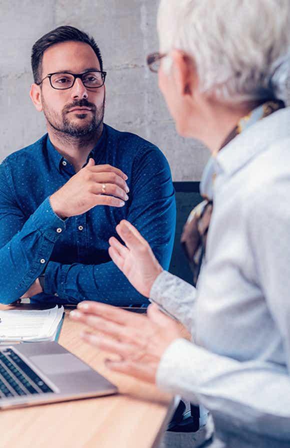 male sales leader in a formal office setting having a difficult yet productive performance conversation with a seller using the framework outlined in the vital conversations manager training module.