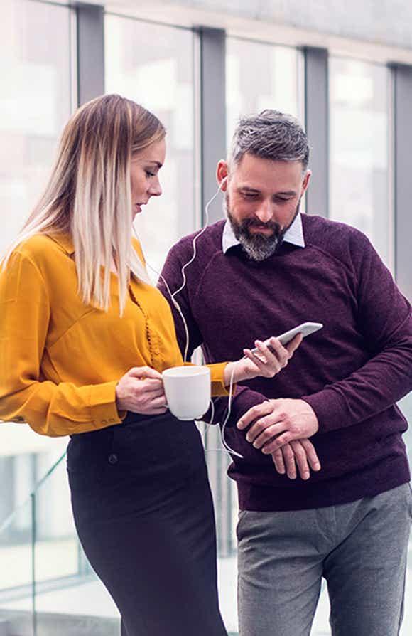 attractive male and female sales professionals looking on a smart phone to review an account plan they learned how to create in richardson's prosperous account strategy training program